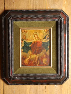 tableau encadré représentant une femme entourée d'anges, posé sur un parquet