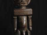 une statue en bois représentant un homme avec un crâne sur la tête