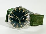 an image of a watch with a green strap on a white surface