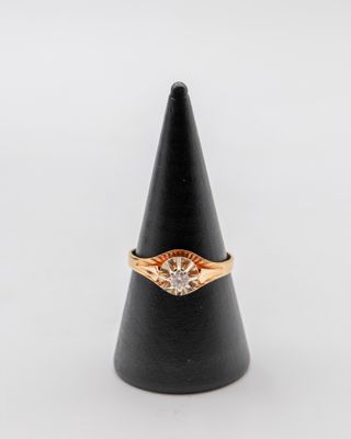 une bague en or et diamants posée sur un cône noir
