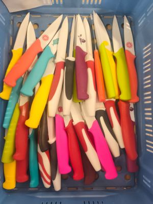 de nombreux couteaux de différentes couleurs dans un panier bleu