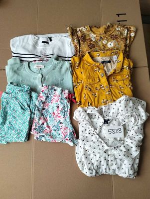 four baby clothes laid out on top of a cardboard box