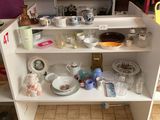un placard blanc sur lequel sont posés de nombreux plats et tasses