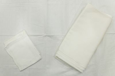 deux serviettes blanches posées sur une nappe blanche, sur une table