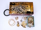 une boîte en bois remplie de bijoux variés, posée sur une surface blanche