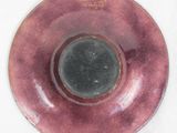 a pink plate with a black center on a white surface