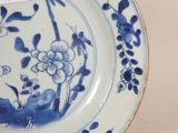 a blue and white plate with flowers and birds on it