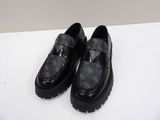 black loafer shoes with a bow on top of a white surface