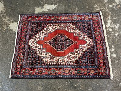 a red and black rug on a concrete floor