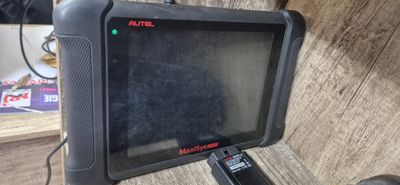 une tablette noire posée sur une table, avec une télécommande à côté