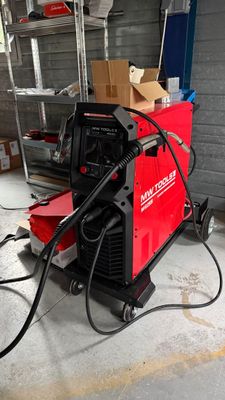 a red welding machine in a garage with a box on the floor