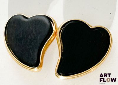 une paire de boucles d'oreilles noires et dorées en forme de cœur sur un fond blanc