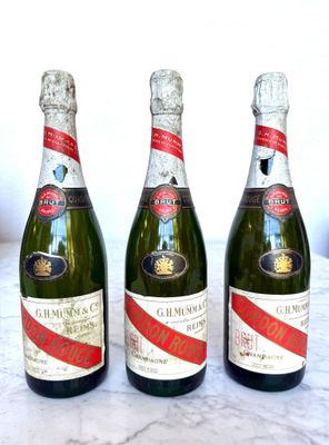 Trois bouteilles de champagne sont alignées sur une table en marbre