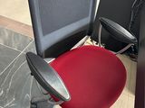 une chaise de bureau rouge placée devant un bureau noir