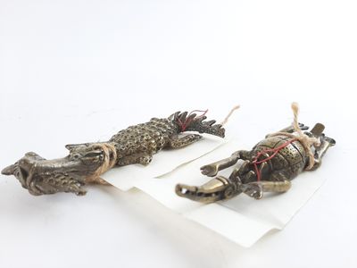two small figurines of animals on a white surface