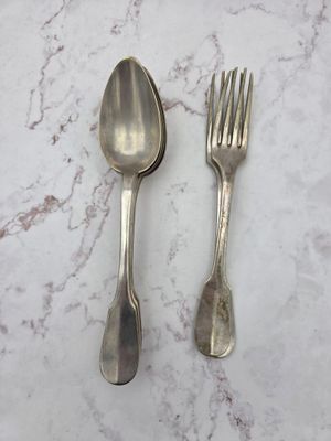 deux cuillères en argent et une fourchette posées sur une table en marbre