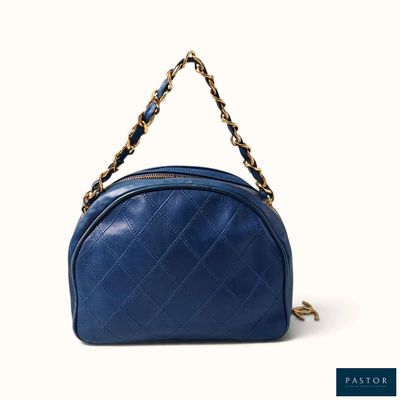 un sac à main bleu muni d'une bandoulière en chaîne, sur fond blanc
