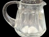 un pichet en verre transparent muni d'une anse, sur fond noir