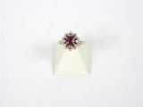 un gros plan d'une bague ornée d'une pierre rouge sur un fond blanc