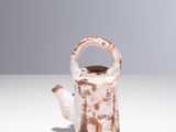un petit vase muni d'une anse, posé sur une table