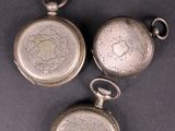 three antique silver pocket watches are sitting on a table