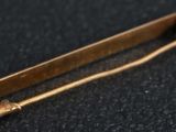 a close up of a gold safety pin on a black surface