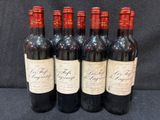 six bouteilles de vin rouge sont alignées sur une table