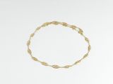 gros plan d'un bracelet en or sur une surface blanche