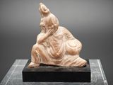 une statue représentant un homme assis sur un bloc de marbre