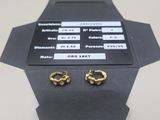 two pairs of gold earrings sitting on a black box