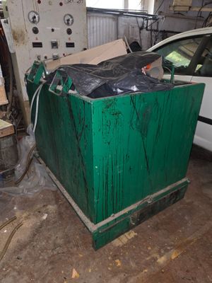 une boîte verte dans un garage, avec une voiture en arrière-plan