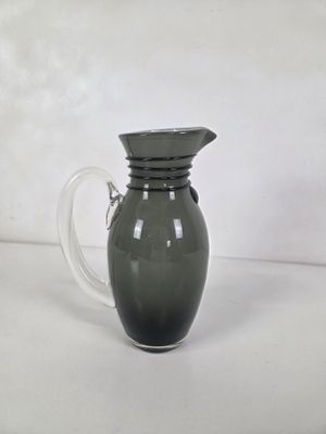 un pichet en verre vert muni d'une anse, posé sur une table
