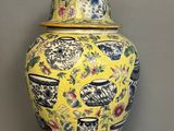 yellow and blue vase with lid on wooden stand on grey background