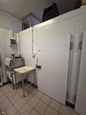 une photo d'une cuisine avec une table et des réfrigérateurs