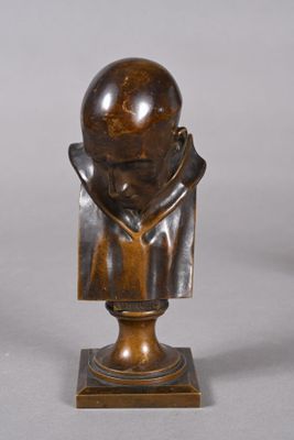 bronze bust of a man with a hat on top of a wooden base