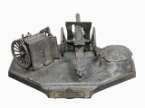 une maquette en métal représentant un canon et une roue, posée sur un socle