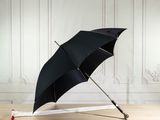 a black umbrella sitting on a wooden floor next to a white wall