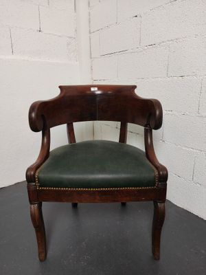 une chaise ancienne en bois dont l'assise est recouverte de cuir vert