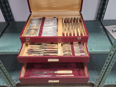 beaucoup d'argenterie dans un coffret rouge posé sur une étagère