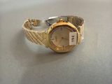 une montre-bracelet en or sur laquelle est accrochée une étiquette blanche
