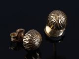 un gros plan sur une paire de boucles d'oreilles en or posées sur une surface noire