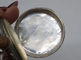 a close up of a person holding a silver pocket watch