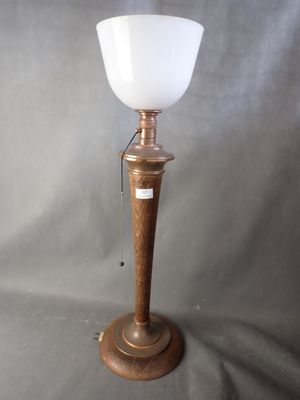 une lampe en bois surmontée d'un abat-jour en verre blanc