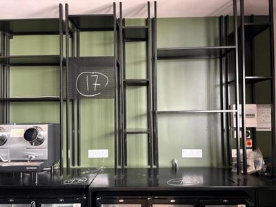 une étagère noire sur laquelle est posée une horloge, dans une pièce