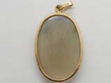 a close up of a yellow gold pendant with a white background