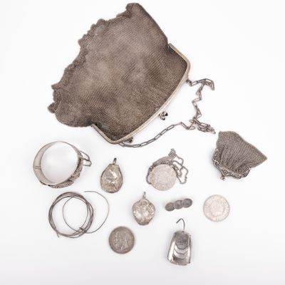 an assortment of silver jewelry including a purse, ring, and other items