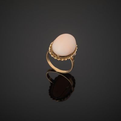 a gold ring with a white stone on a black surface