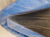 a blue plastic cover on a bed with a white sheet