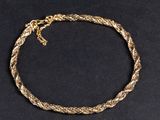gros plan d'un bracelet en chaîne en or sur une surface noire