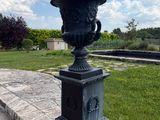a large black urn sitting on the side of a stone walkway